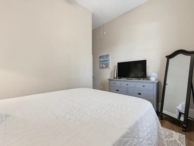 Suite 314A queen bedroom historic Savannah condo rental â€” floating TV shelf natural light curtains