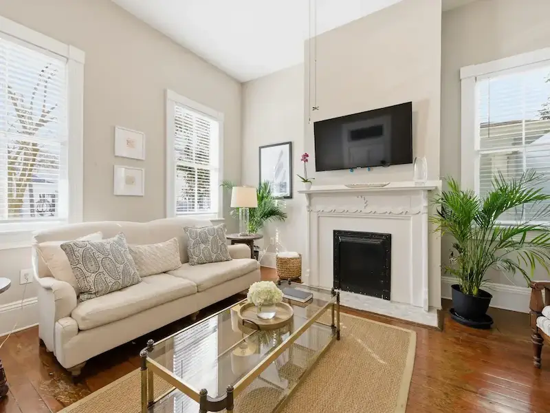Suite 314A living room at The Wilder House Savannah â€” heart-pine floors striped armchairs fireplace and open view to maroon kitchen island