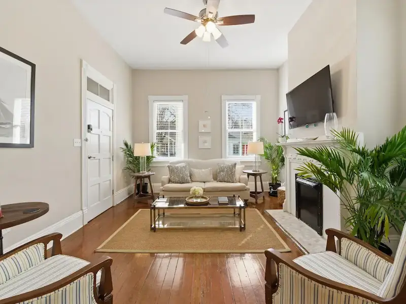 Suite 314A Victorian District Savannah living room â€” cream sofa, glass coffee table and ornate fireplace mantle