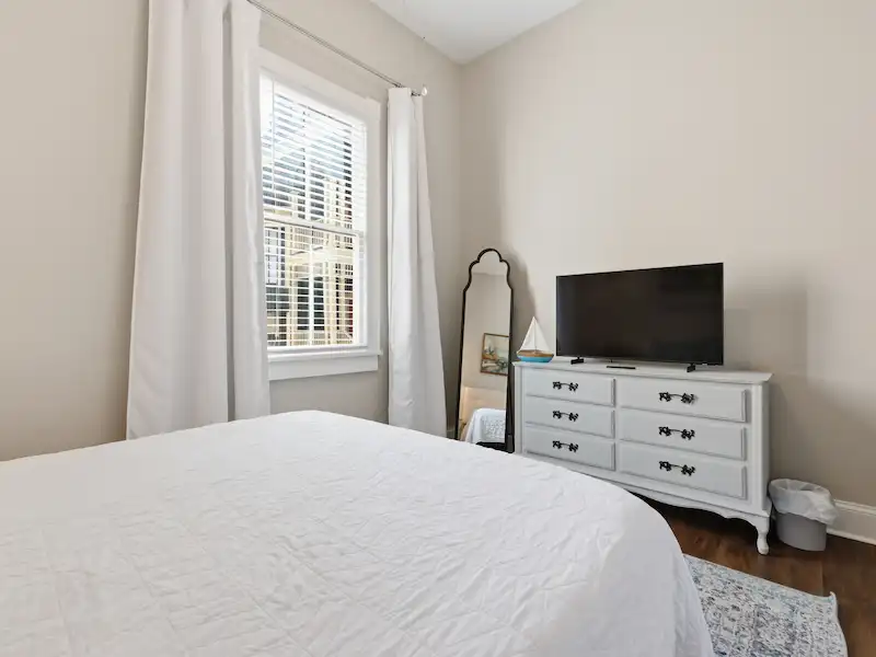Suite 316A queen bedroom at The Wilder House Savannah â€” white bedding blue accent pillows large window and natural light