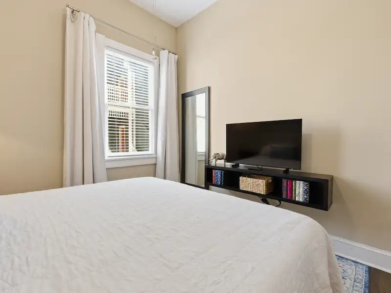 Suite 316A king bedroom at The Wilder House Savannah â€” tufted headboard premium white linens blue accent pillows natural light