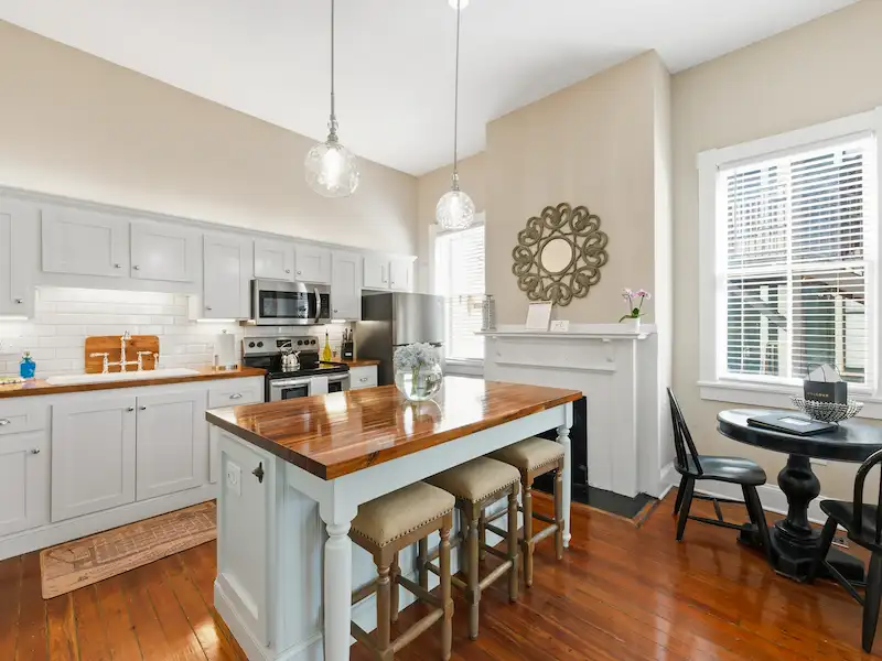 Suite 316A kitchen with haint blue island, pendant lights and fireplace â€” Victorian District Airbnb Savannah