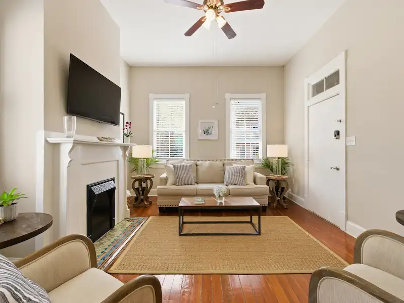 Suite 316A living room at The Wilder House Savannah â€” original heart-pine floors fireplace smart TV and open view to haint blue kitchen